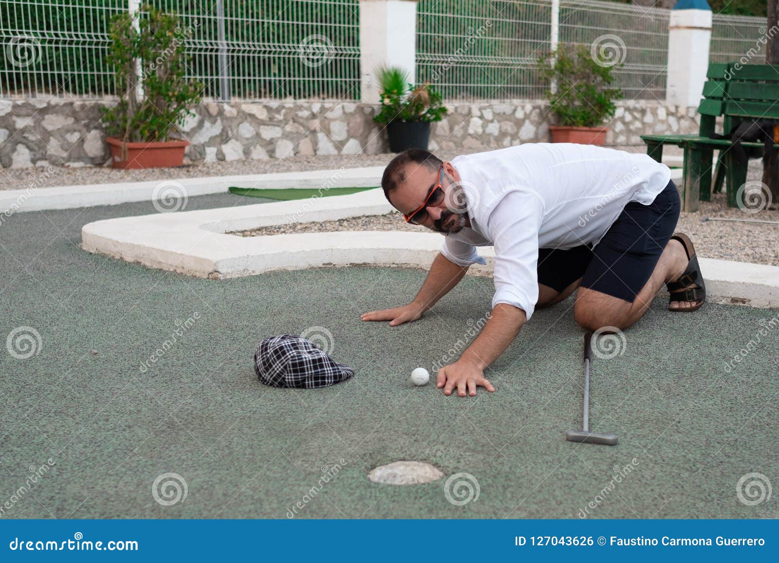 Man Looking at Golf Ball with Stick in Hand before Throwing Stock Photo
