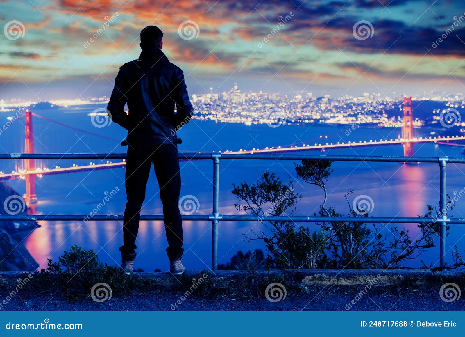 man looking the magnificent view of the golden gate bridge at dawn with the bay bridge in background