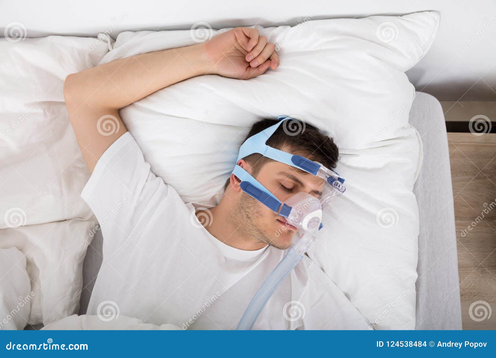 Man Lying on Bed with Sleeping Apnea and CPAP Machine Stock Photo