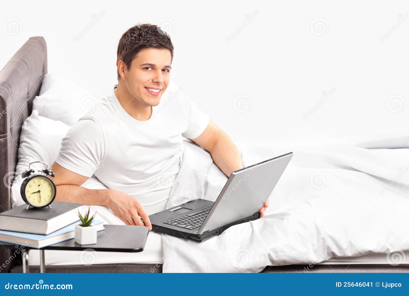 Man Lying On A Bed And Working On A Laptop Stock Image 