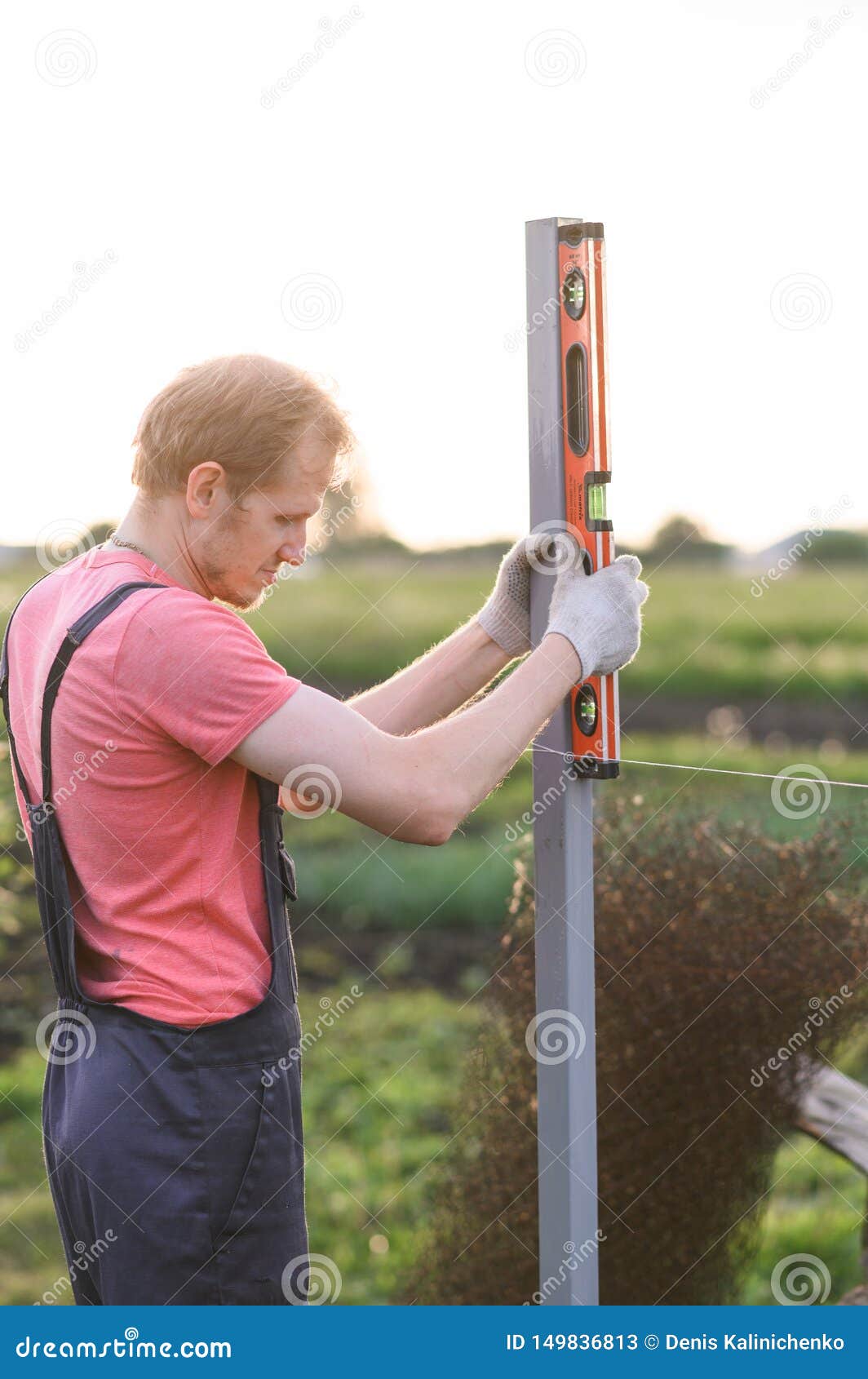 Man Measures the Level. Male Specialist in Outdoor Checking the Post