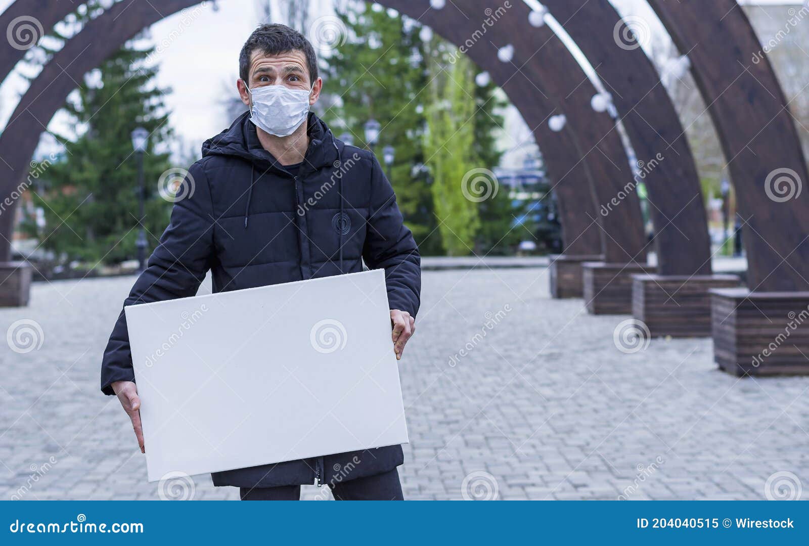 man and in a medical mask on a face keeps in black clothes before himself a net canvas for drawing