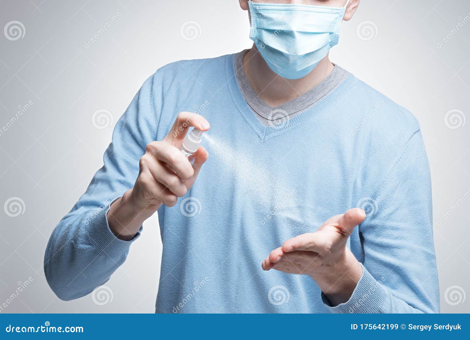 a man in a medical protective masked face mask, a means of protection against the virus, uses a spray to disinfect hands. epidemia