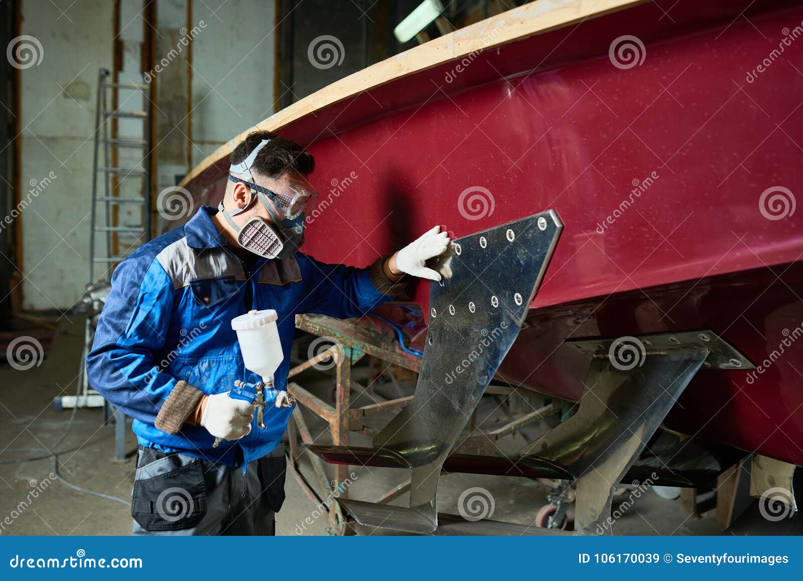 man painting boats in yacht workshop