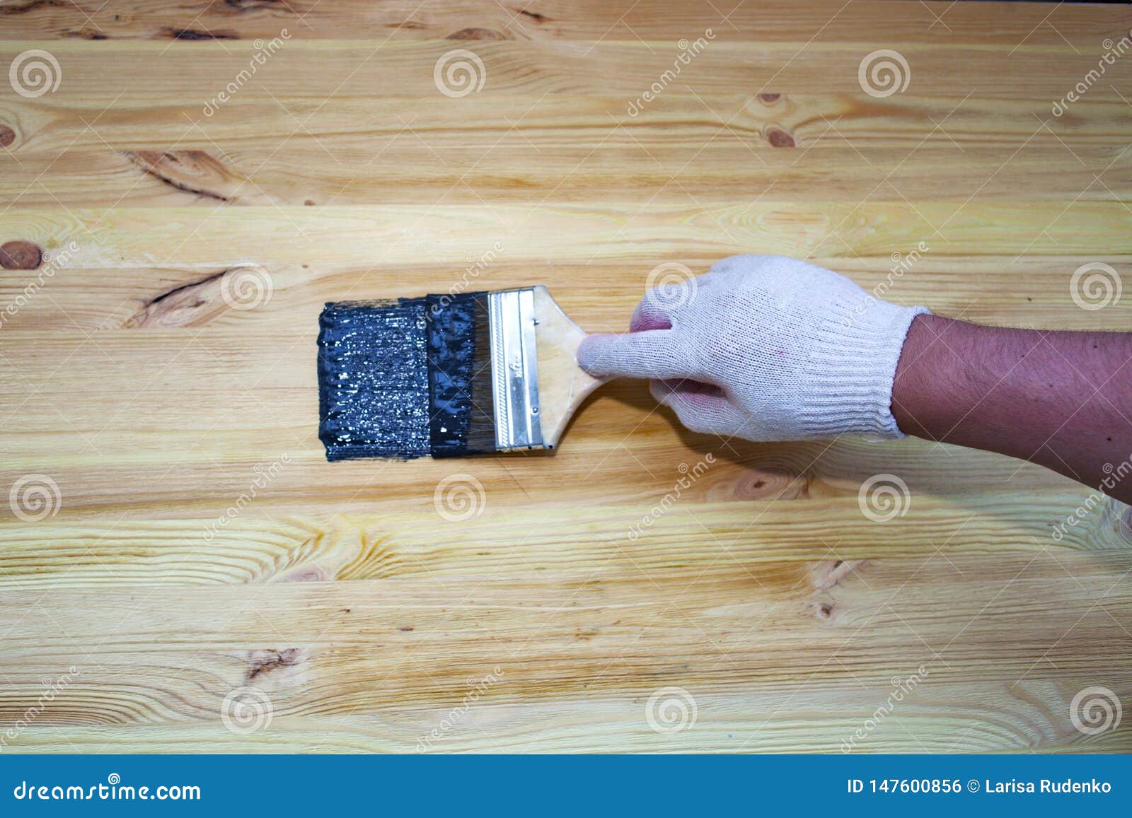 A Man Paints with Black Paint on a Wooden Surface Stock Photo Image