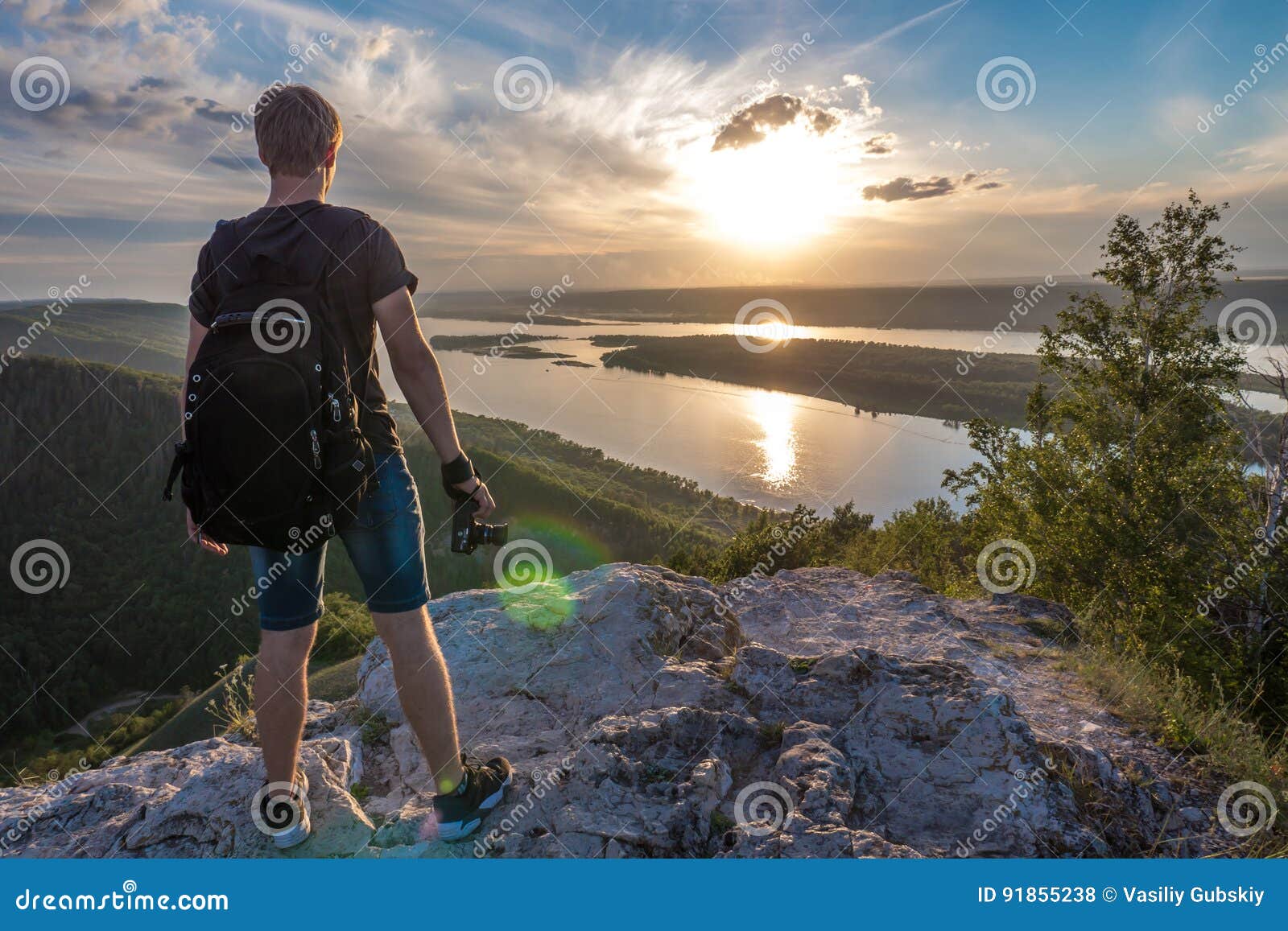 The man is a photographer on top of a mountain watching the sunset