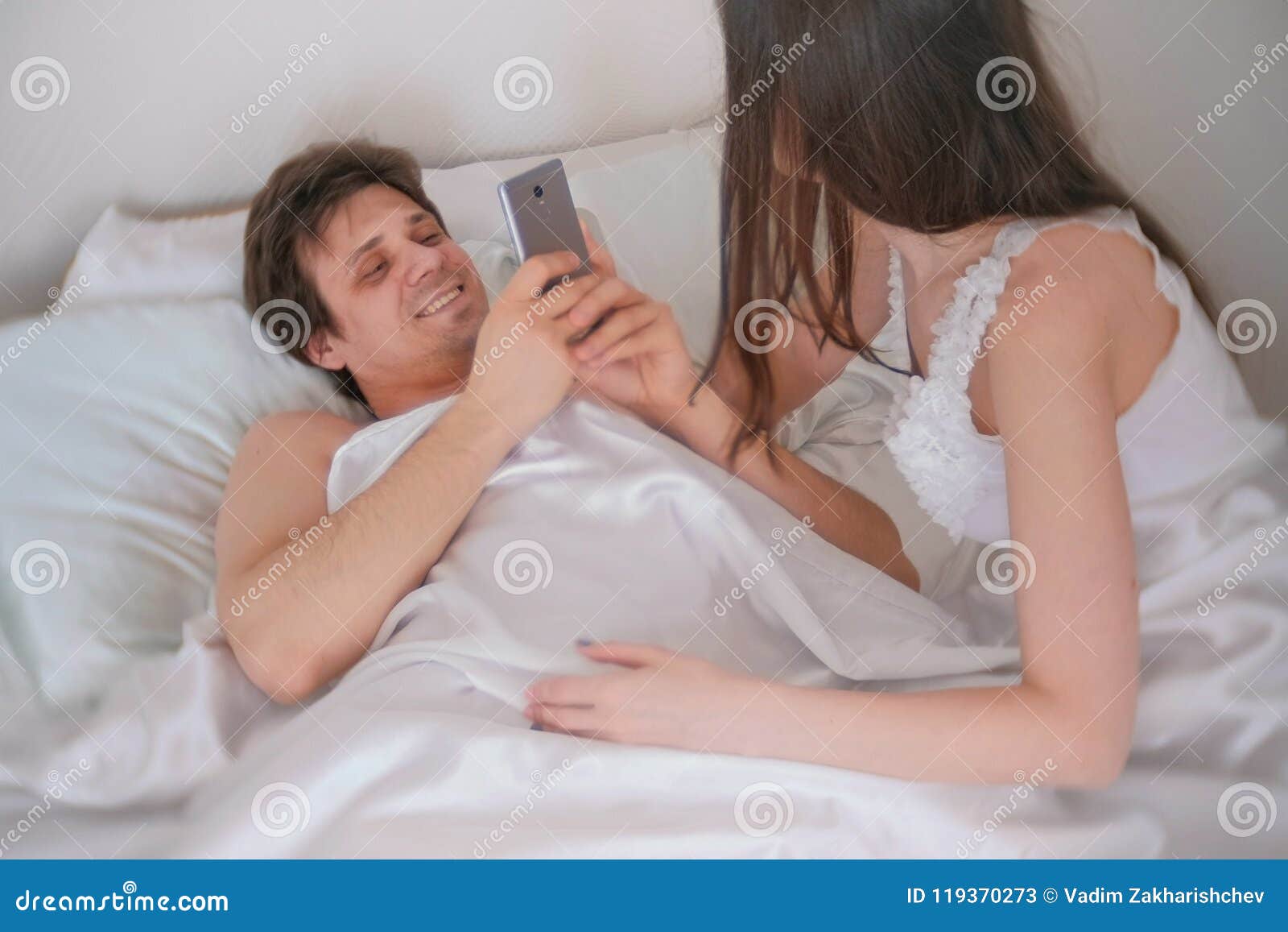 Man Photographs a Woman on Mobile Phone. Couple Man and Woman Lying in