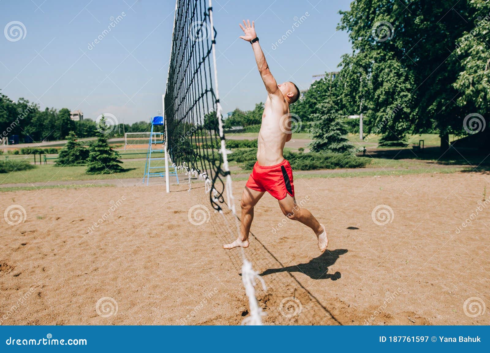 Man Playing Beach Volleyball Diving after the Ball Under a Clear Blue