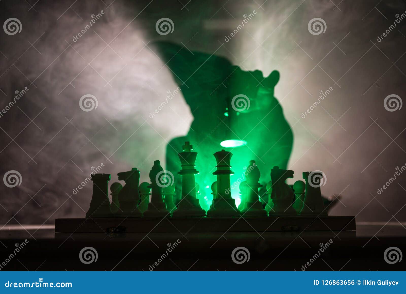 man playing chess. scary blurred silhouette of a person at the chessboard with chess figures. dark toned foggy background.