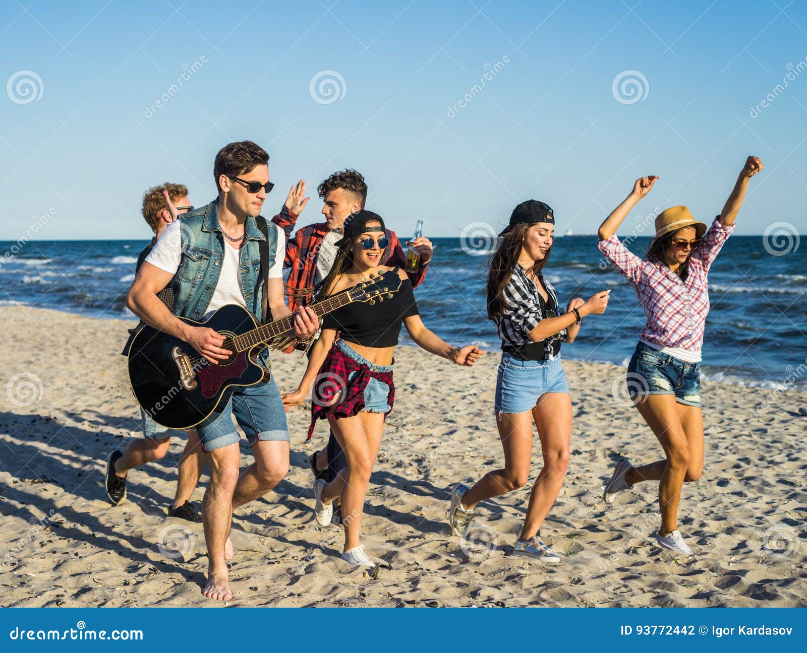 Man Playing Guitar on the Beach and His Friends Dancing Around Him ...