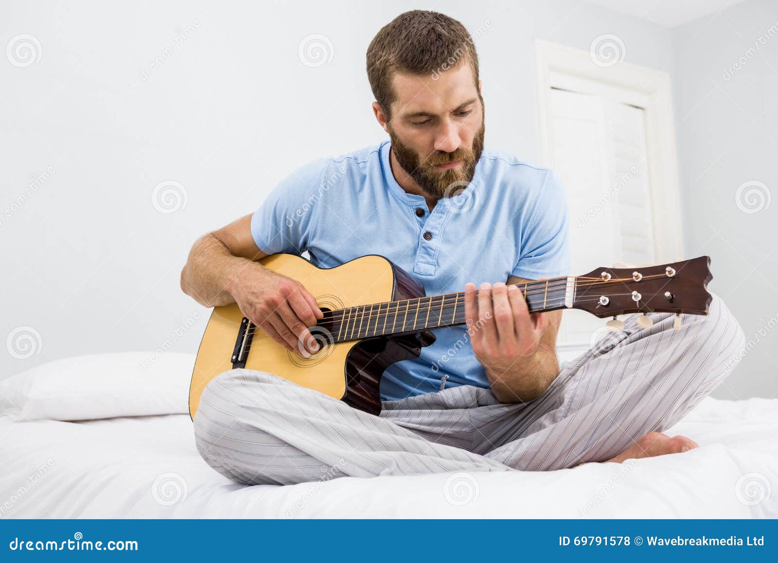 Man playing guitar in bed stock photo. Image of abode 69791578