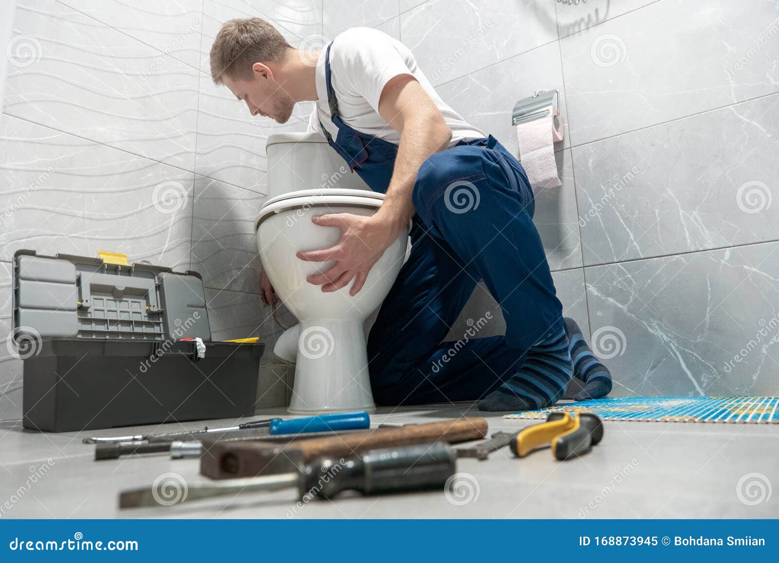 man plumber in uniform installing toilet bowl using instrument kit professional repair service