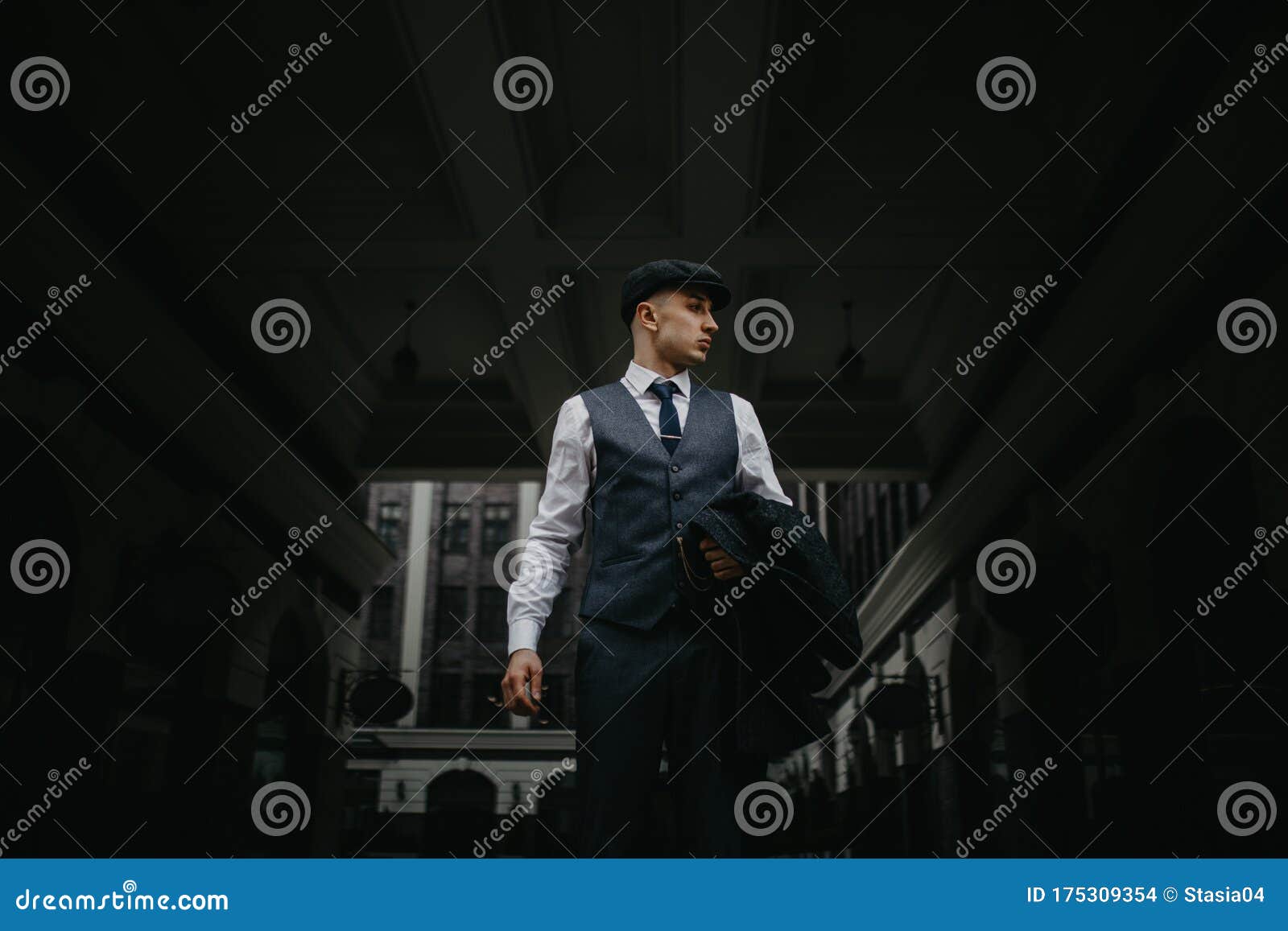 a man posing in the image of an english retro gangster in peaky blinders style at city street