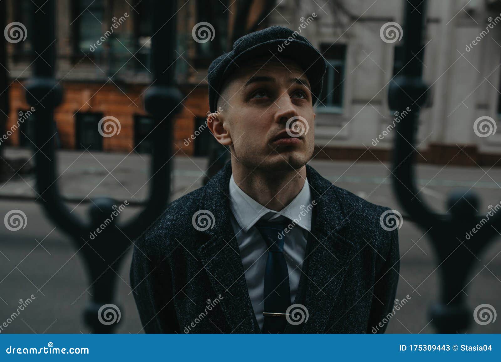 a man posing in the image of an english retro gangster in peaky blinders style at city street