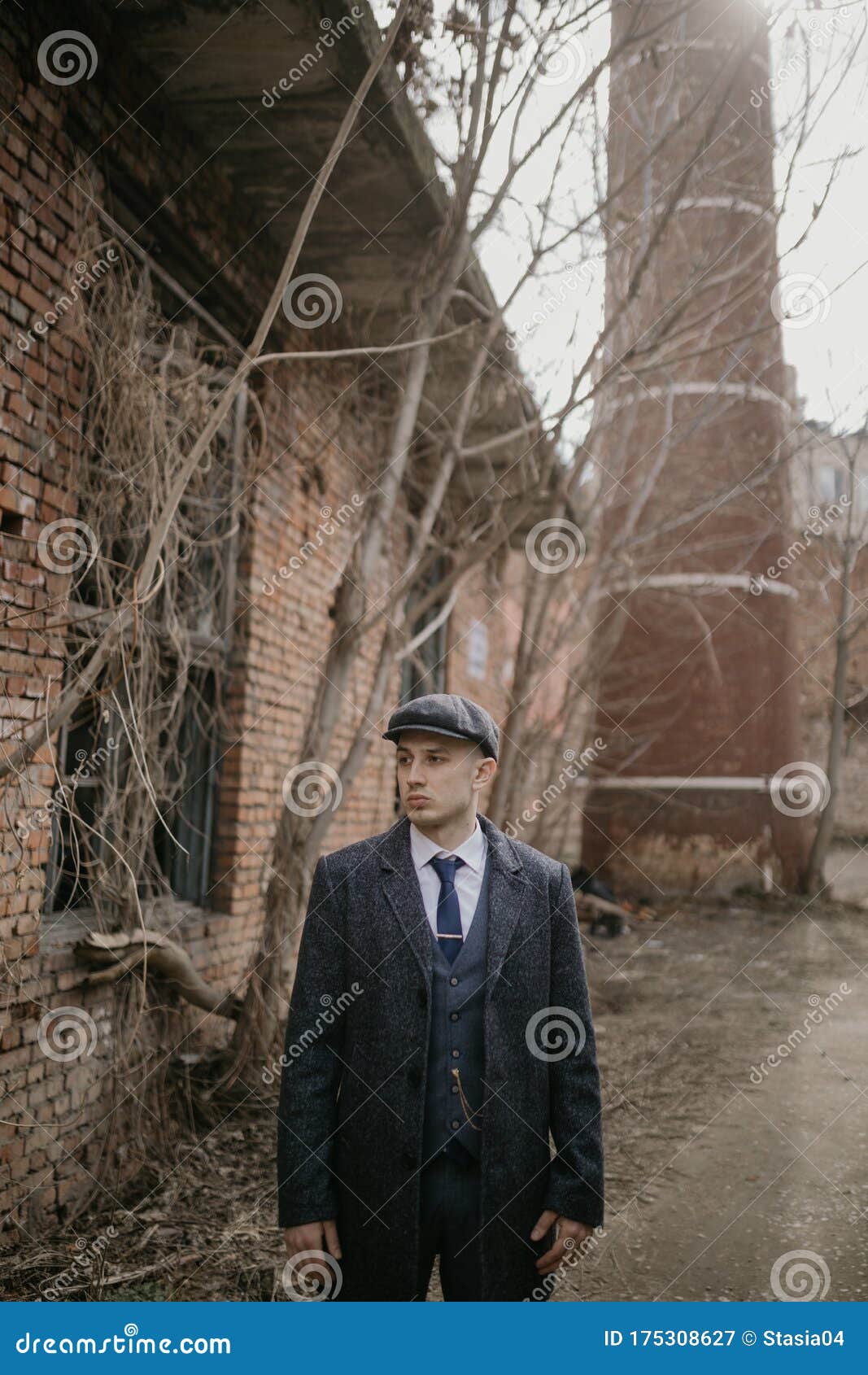 a man posing in the image of an english retro gangster dressed in peaky blinders style near abandoned building