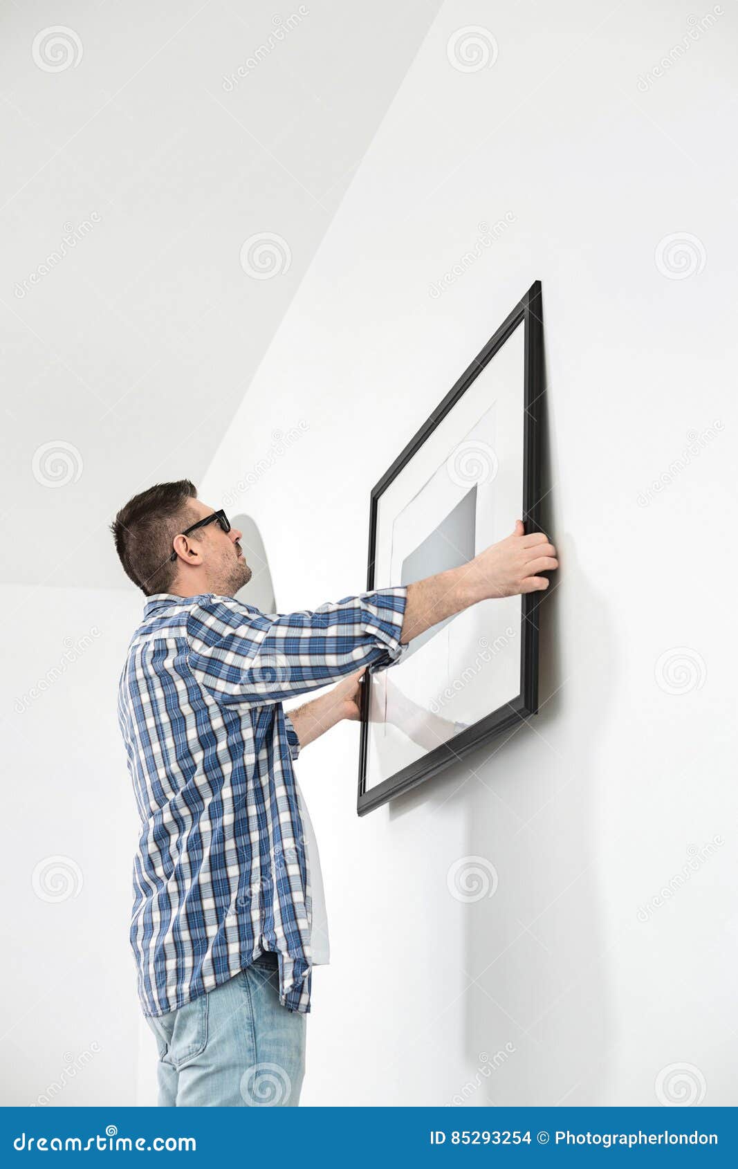 Man Positioning Picture Frame on Wall Stock Photo Image of homeowner