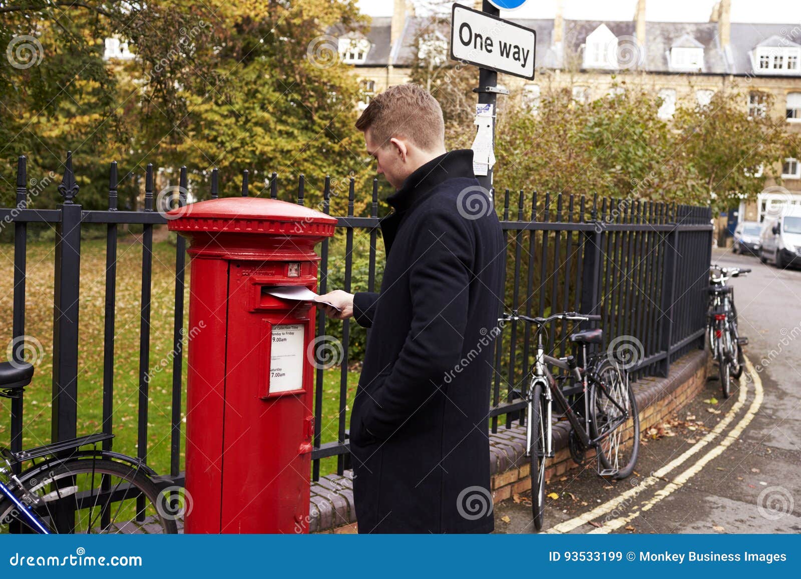 man posting letter in red british postbox