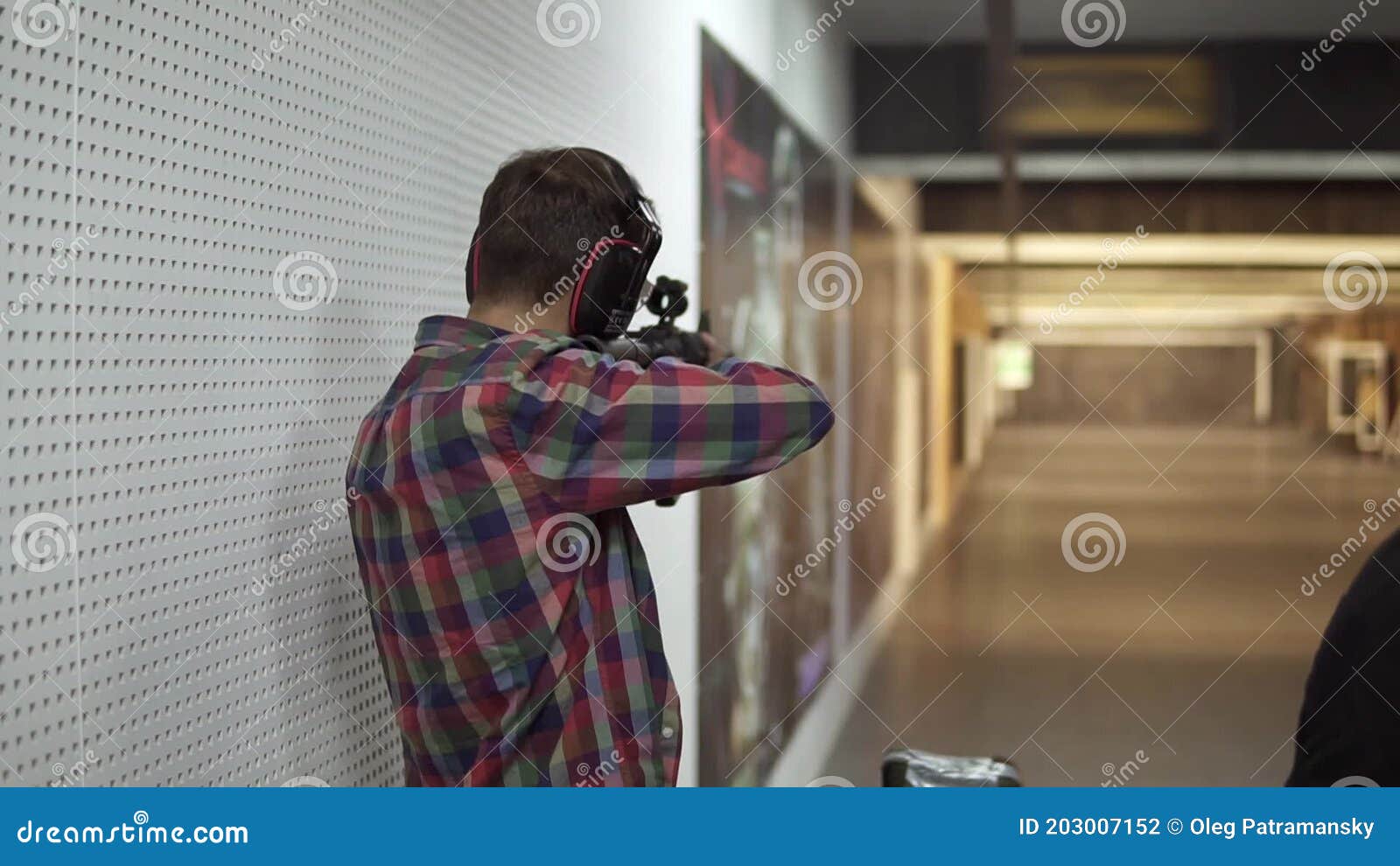 Man Practicing Using a Rifle at Shooting Range in Headphones Stock