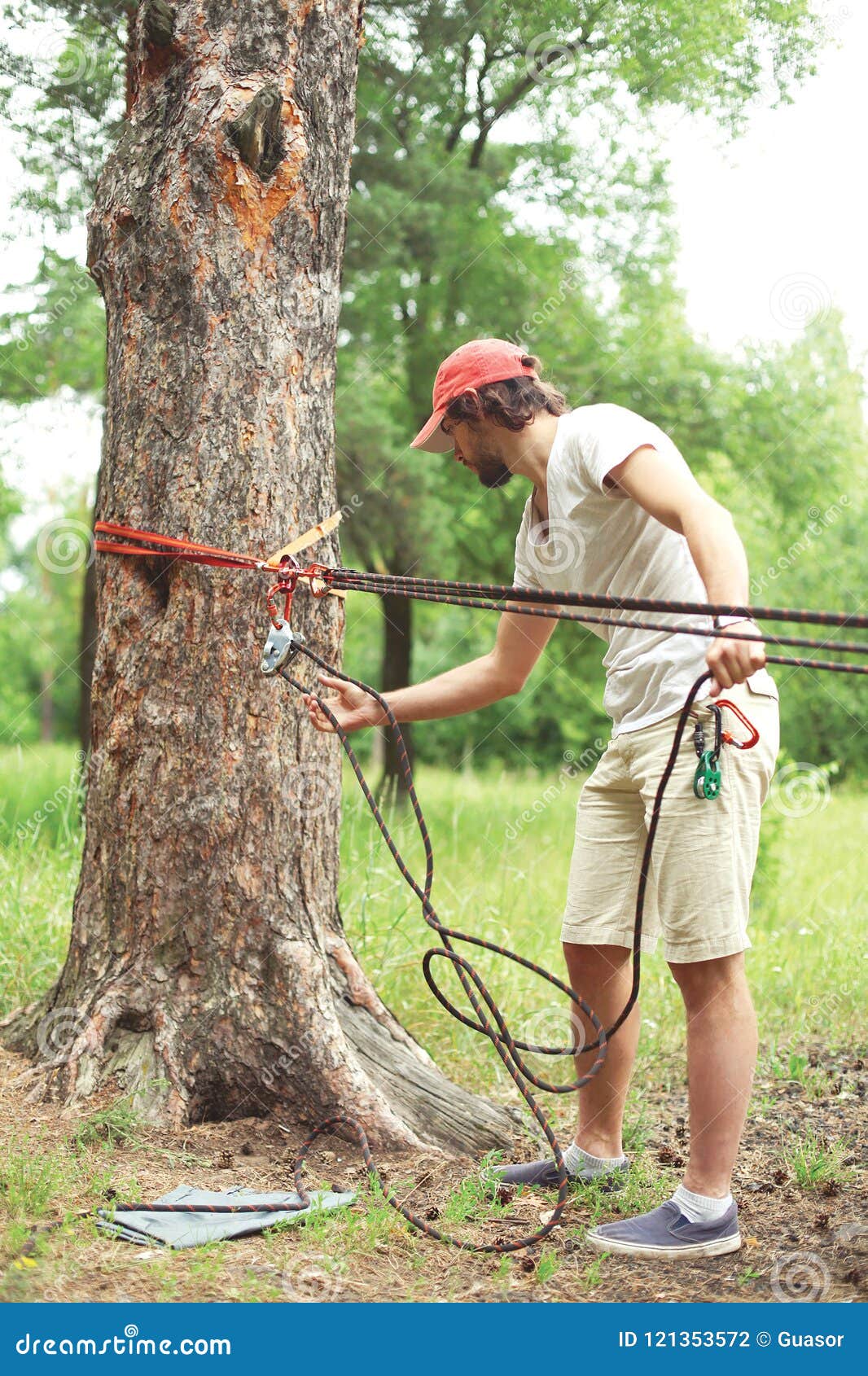 man prepares the equipment fixes secures the rope to the tree