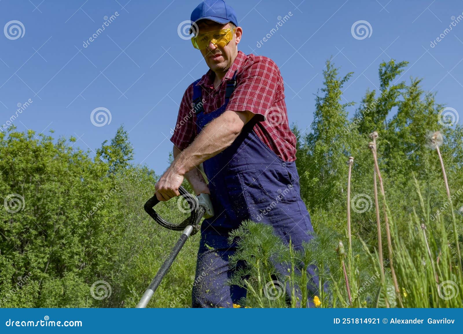 A Man in Protective Glasses Mows the Grass with a Lawn Mower. a Working