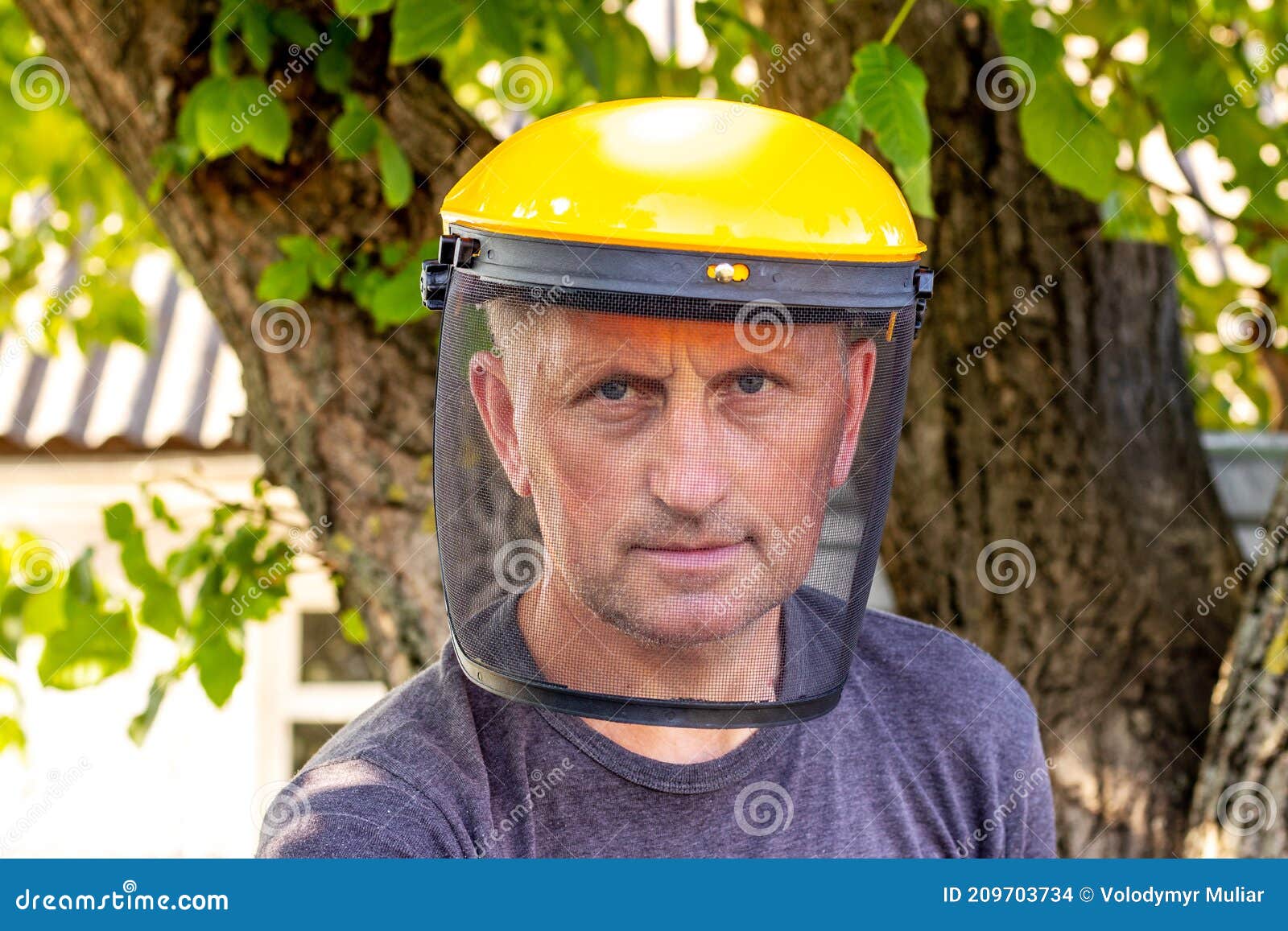 A Man with a Protective Mask for Safety while Mowing the Grass Stock