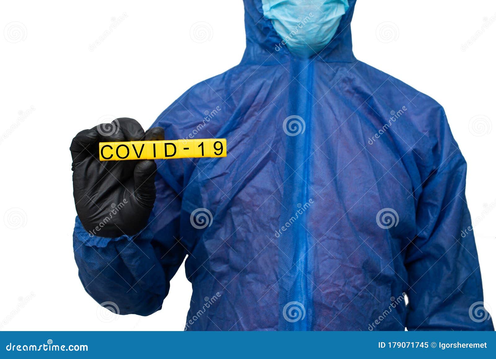 A Man in a Protective Suit and Mask Holds a Sign that Reads Covid 19