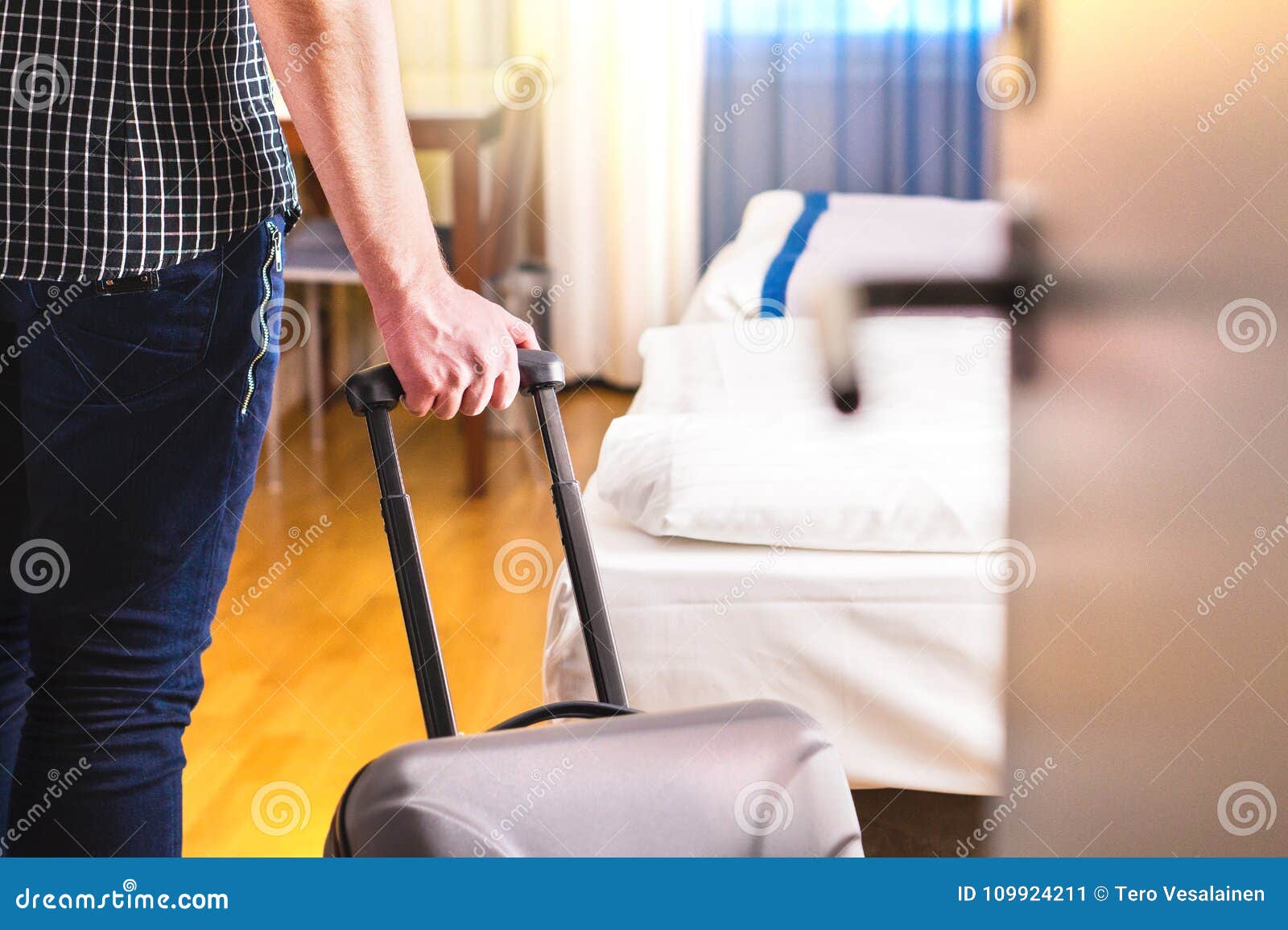 man pulling suitcase and entering hotel room.