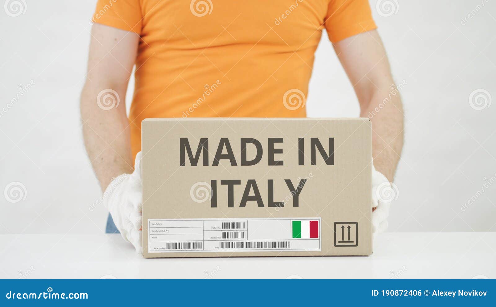 Man Puts Cardboard Box with MADE in ITALY Text on the Table Stock Photo