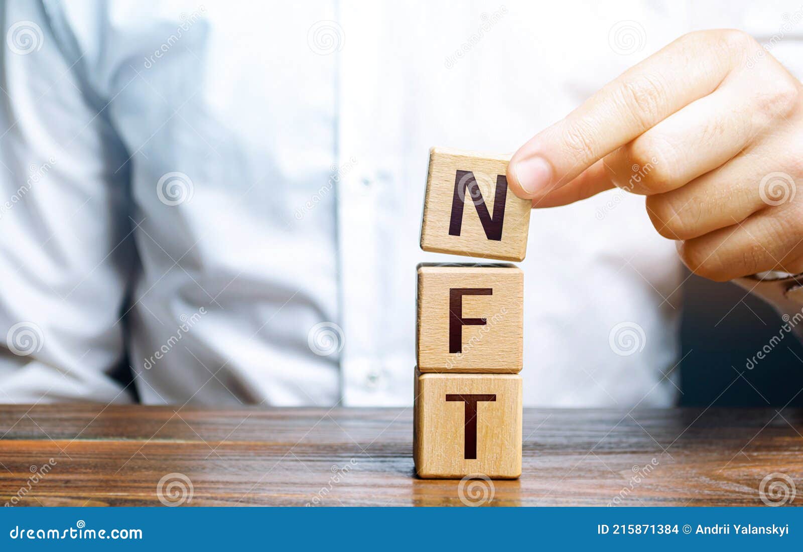 man puts together word nft from blocks. nft non-fungible token. selling digital art assets through internet auctions. blockchain