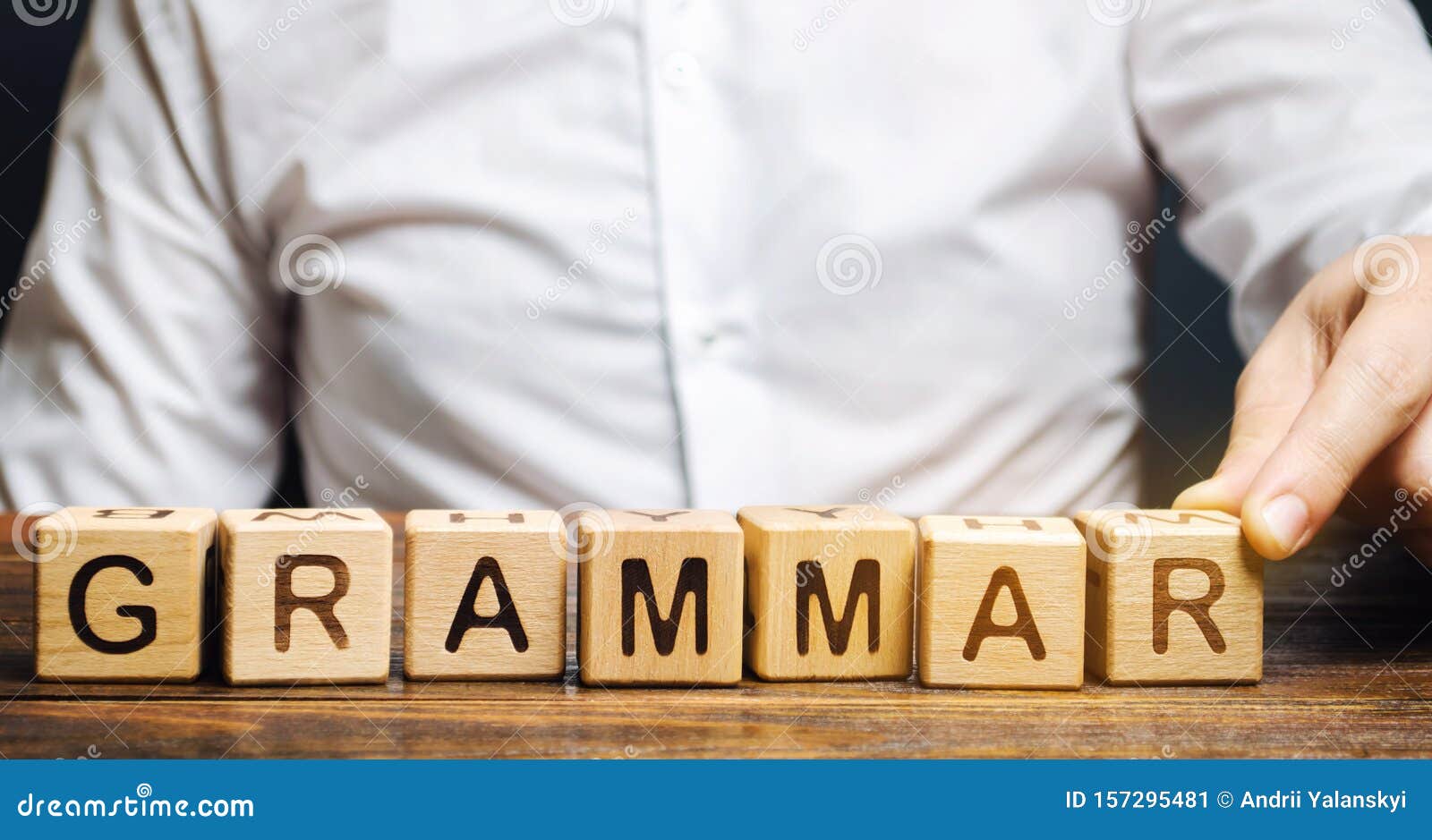 a man puts wooden blocks with the word grammar. set of structural rules governing the composition of clauses, phrases and words in