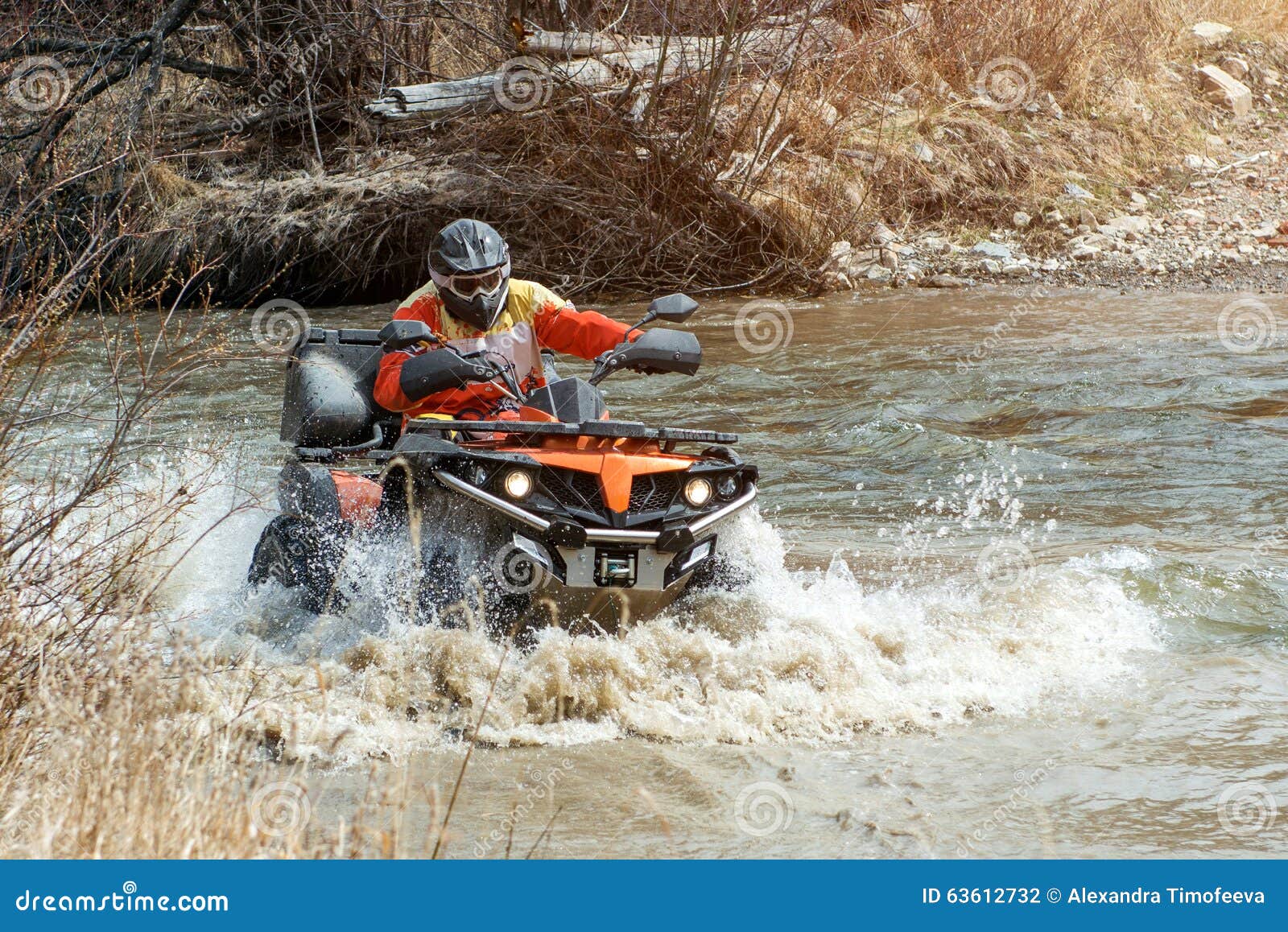 The Man on the Quad Bike Rides on the River with a Splashing Water