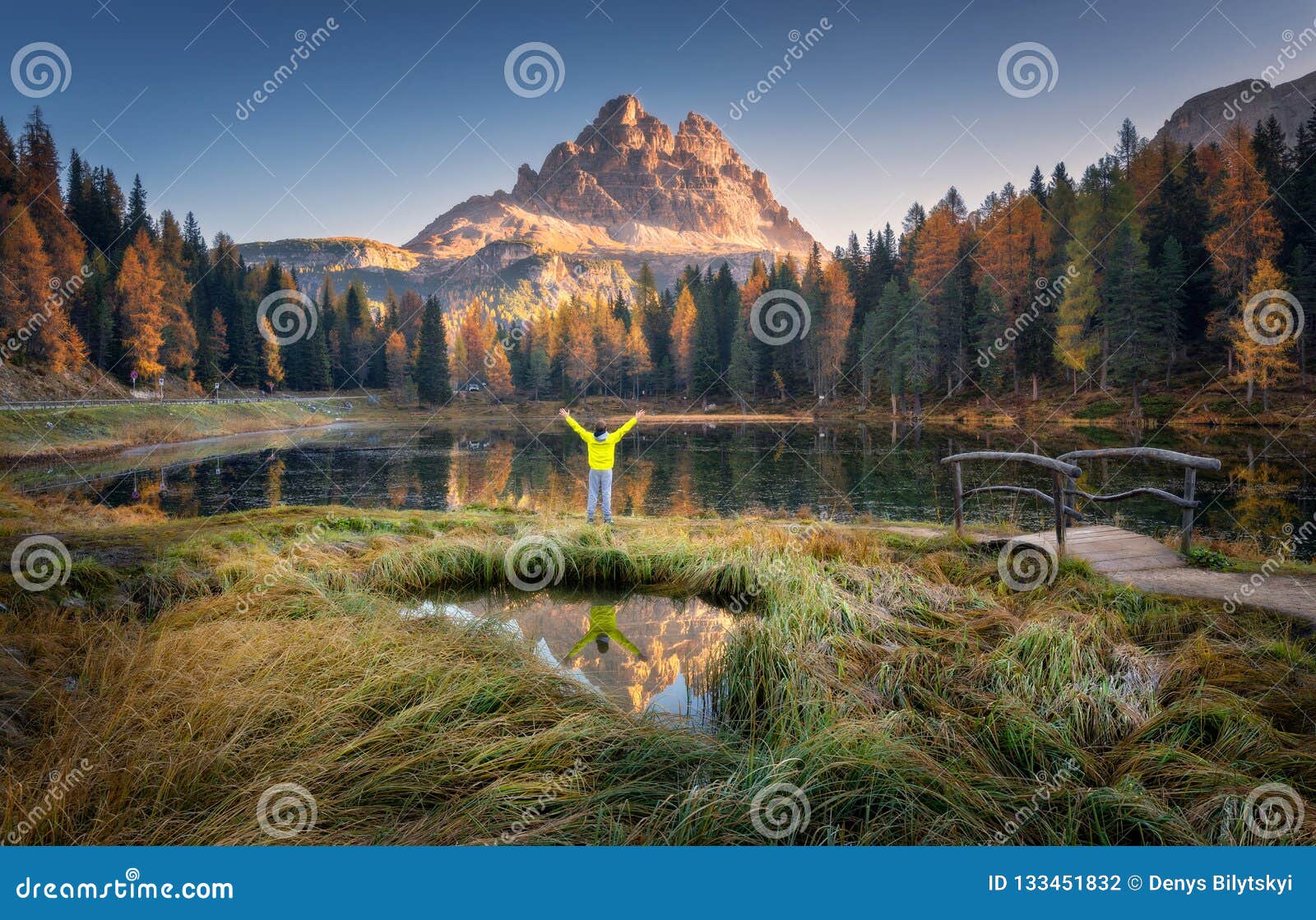 man with raised up arms on antorno lake in autumn at sunrise