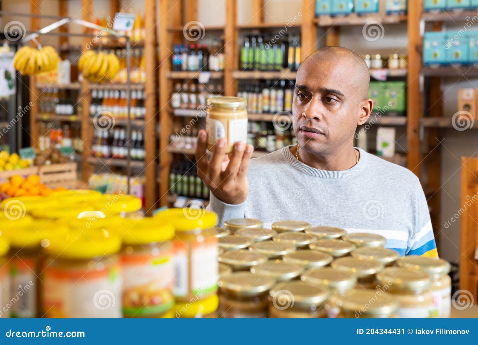 Man Reading Jar Contents On Label While Shopping In Supermarket Stock man-reading-jar-contents-on-label-while-shopping-in-supermarket-stock