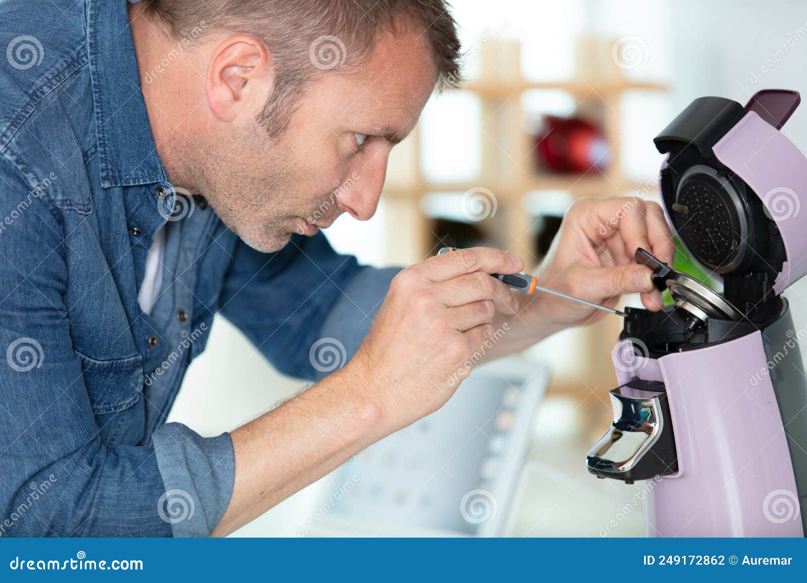 Man Repairing Coffee Machine by Screwdriver in Kitchen Stock Photo