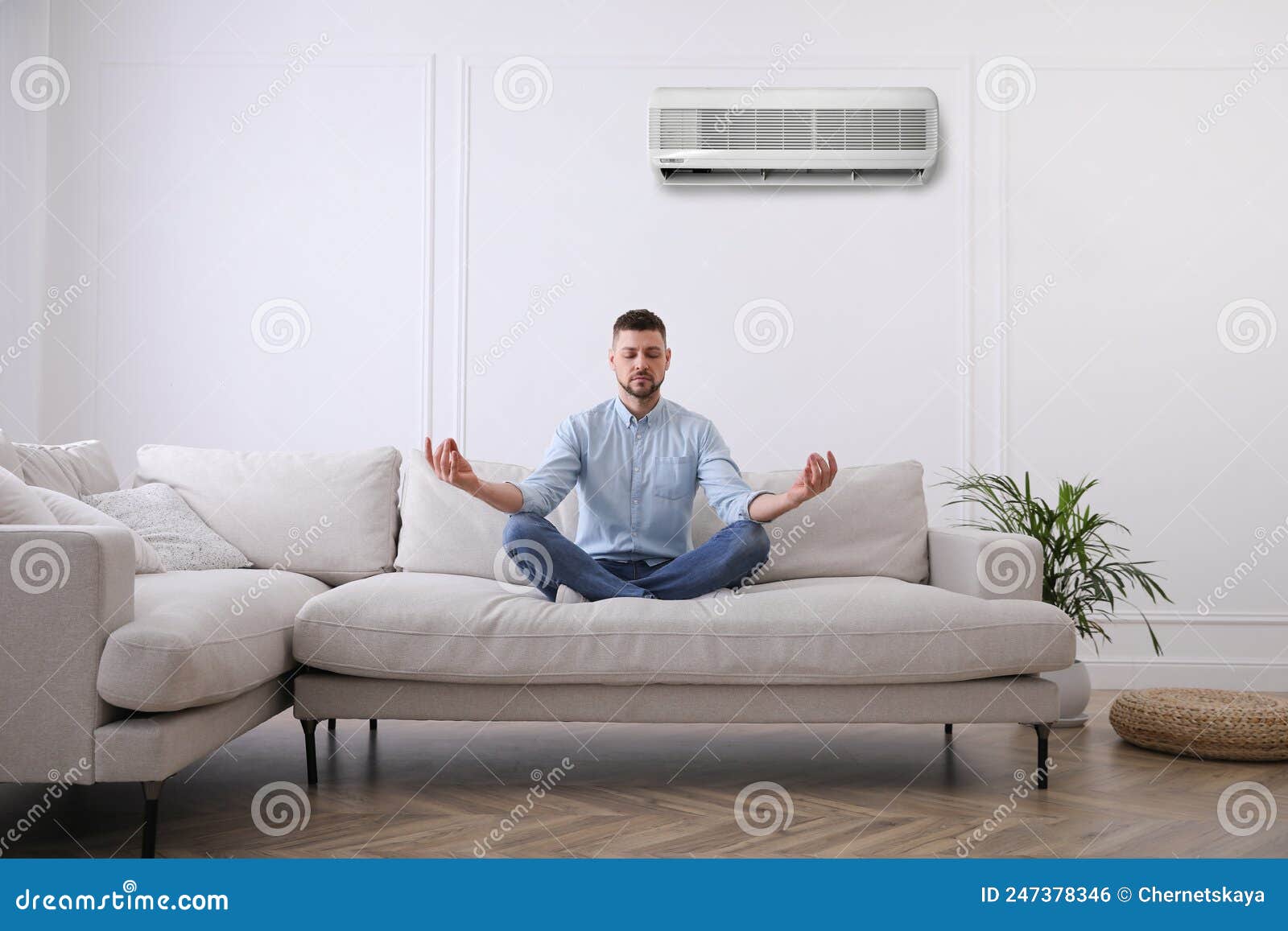 Man Resting Under Air Conditioner on White Wall at Home Stock Photo