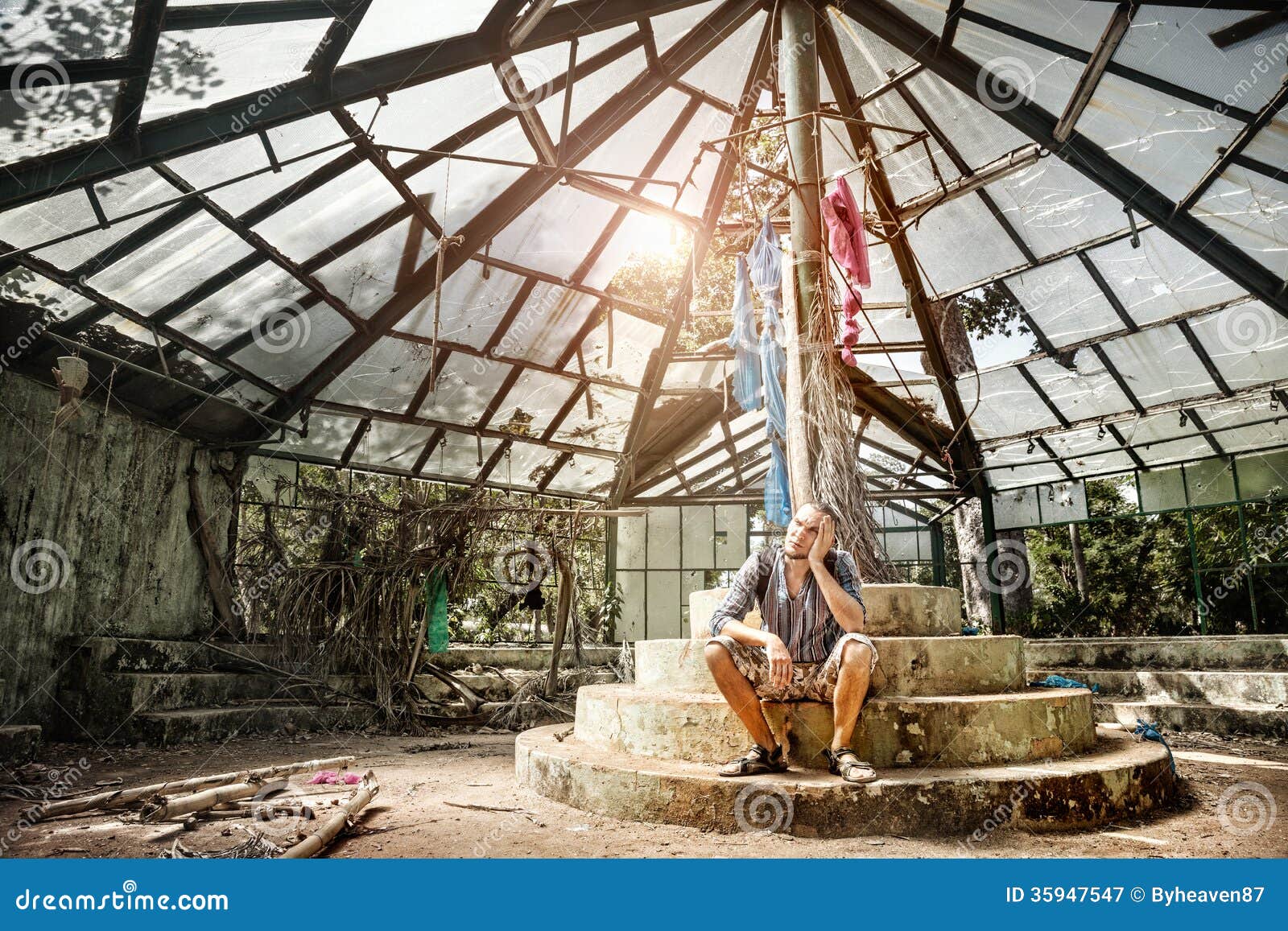 Man in ruined greenhouse. Man sitting in ruined greenhouse in Botanical garden, Puducherry, India