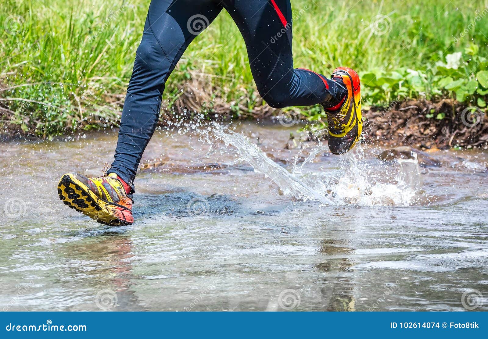 man running in the mountains, crossing a creek