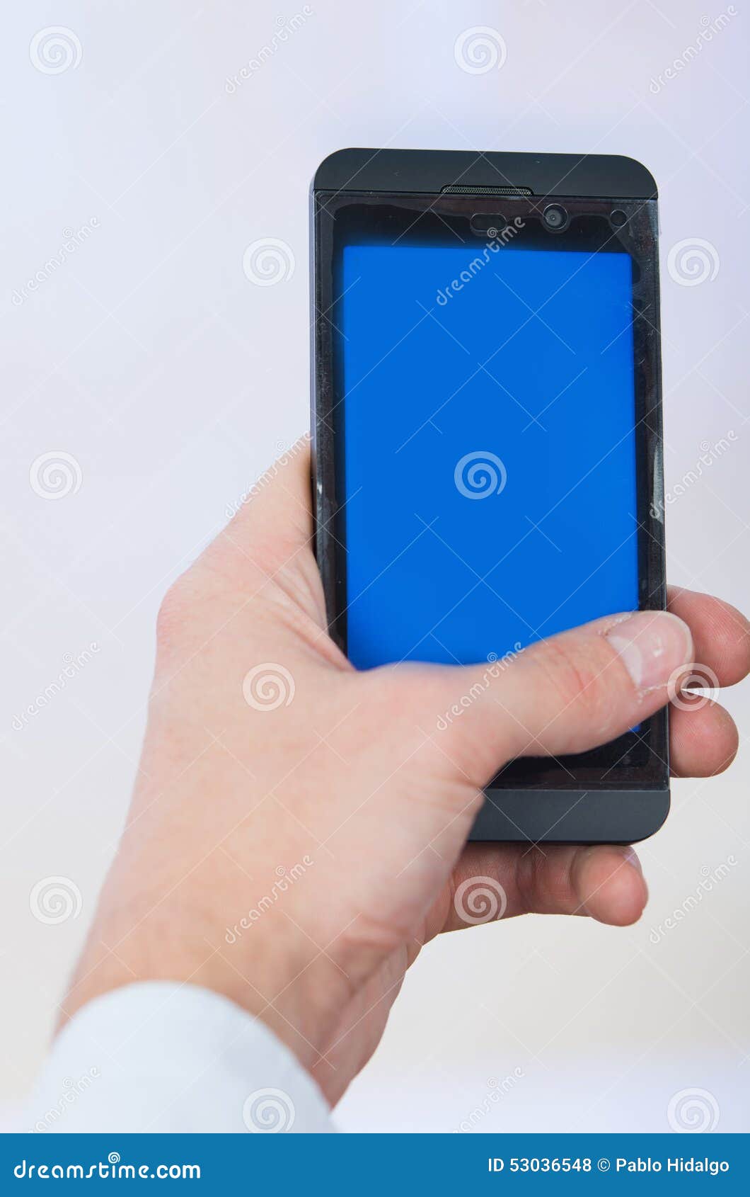 Man s hand holding cell phone with empty blue screen copy space