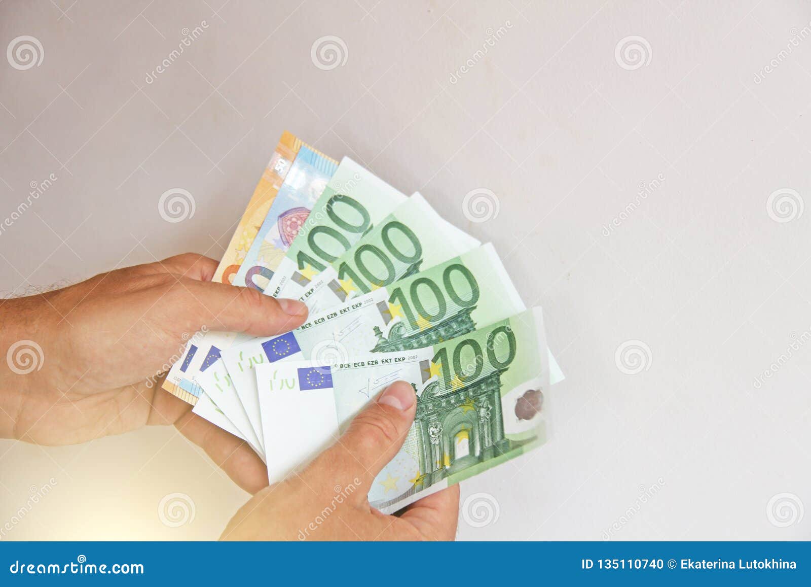 the man`s hand holds the 100 euro, considers them and pays. paper money euros in the hands
