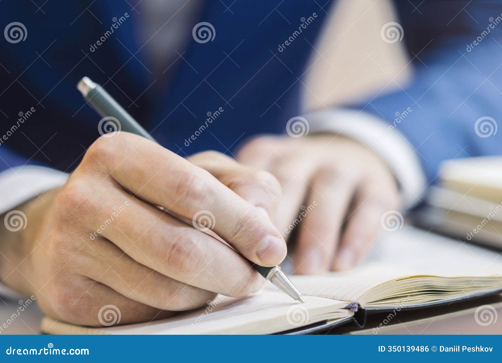 a man's hand inscribing in a notepad, captured closely