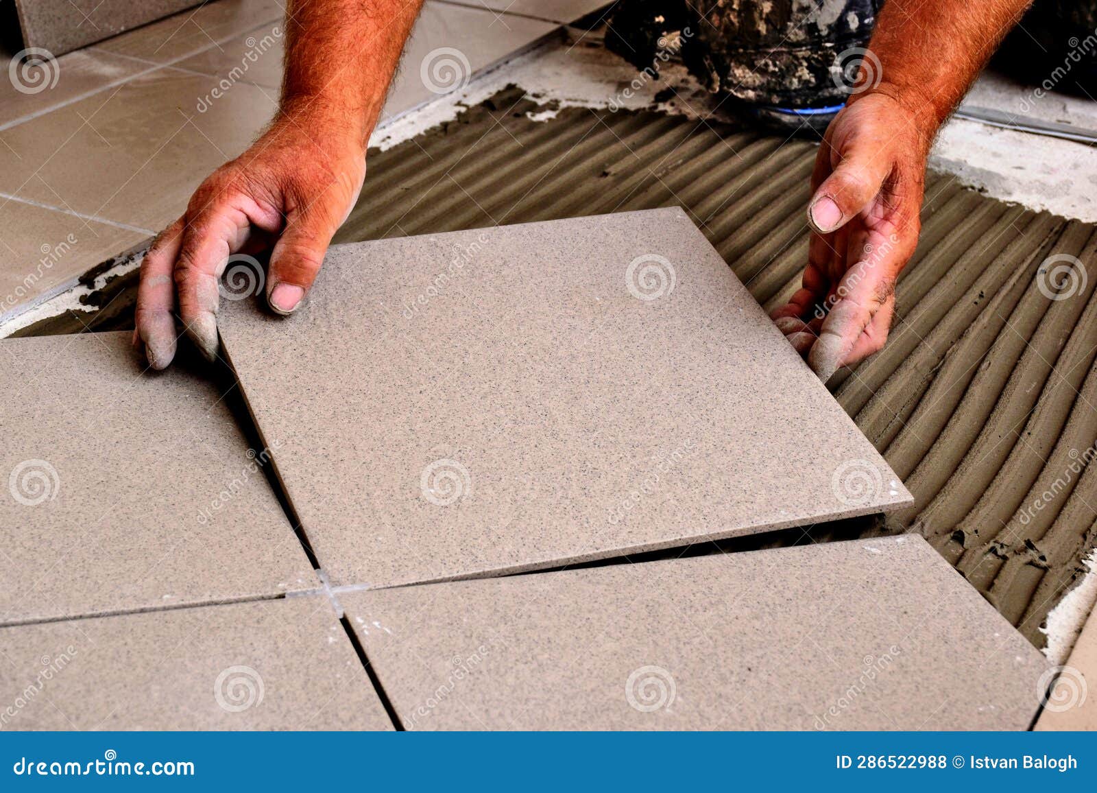 man's hand positioning large ceramic floor tile during flooring installation