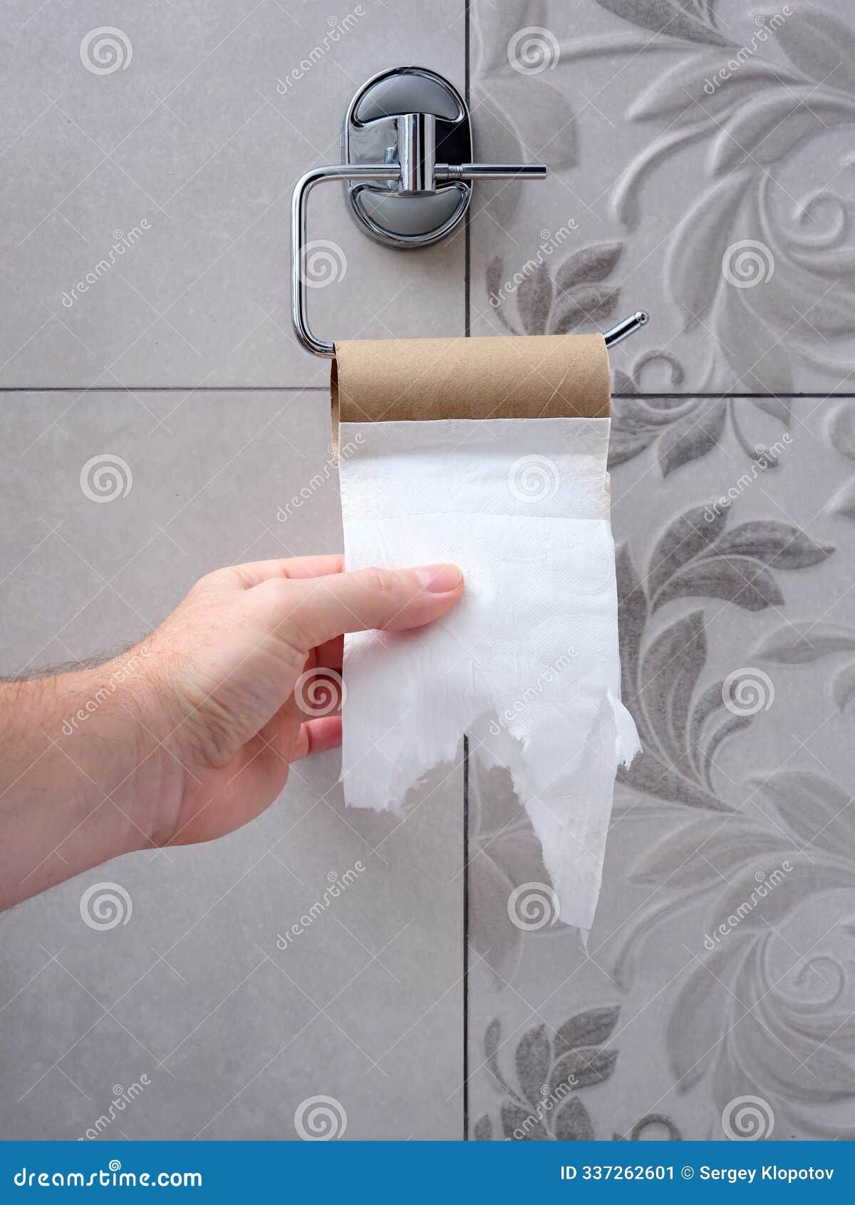 a man's hand reaches for an empty toilet paper holder