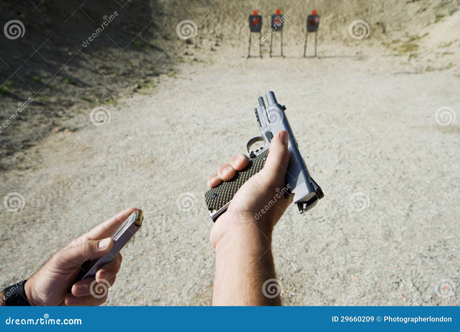 man's hands loading gun at firing range