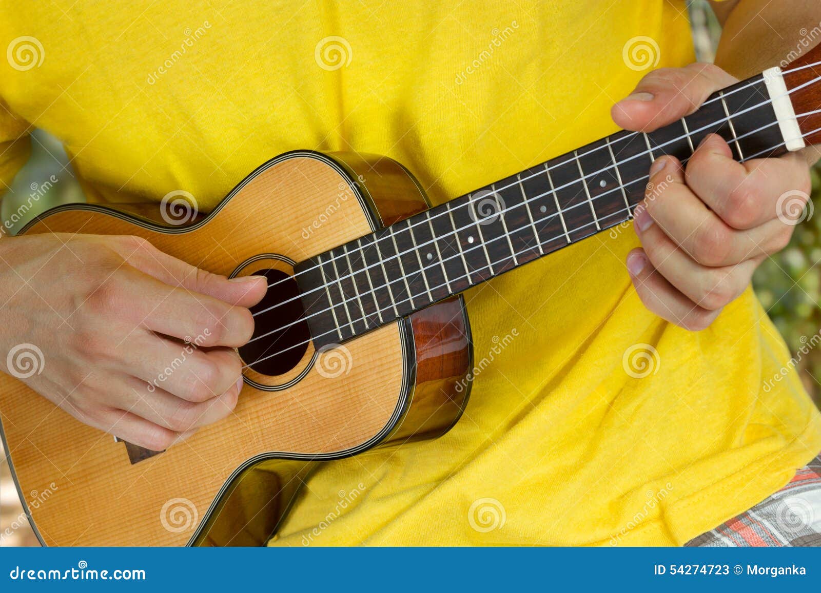 man's hands playing ukulele