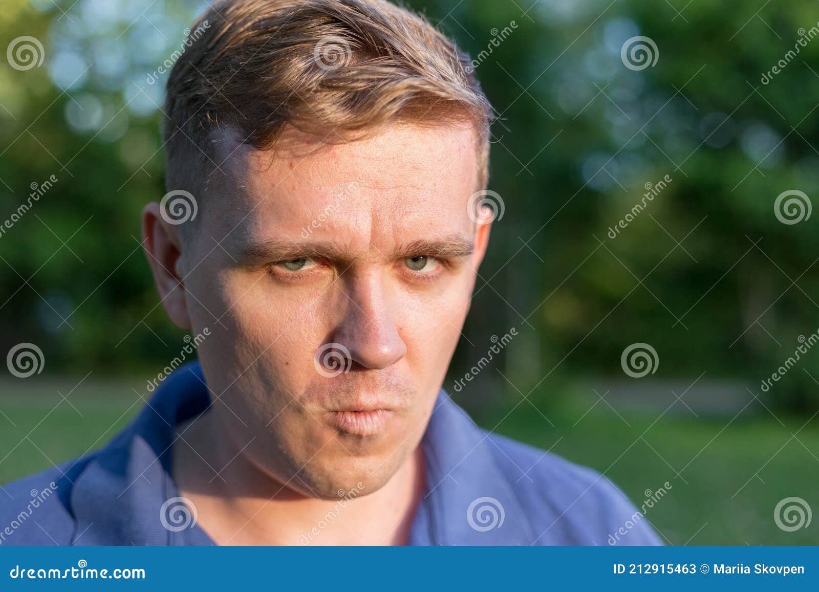 man with a scornful disdainful disrespectful look. portrait of a young guy on nature background, feelings and people