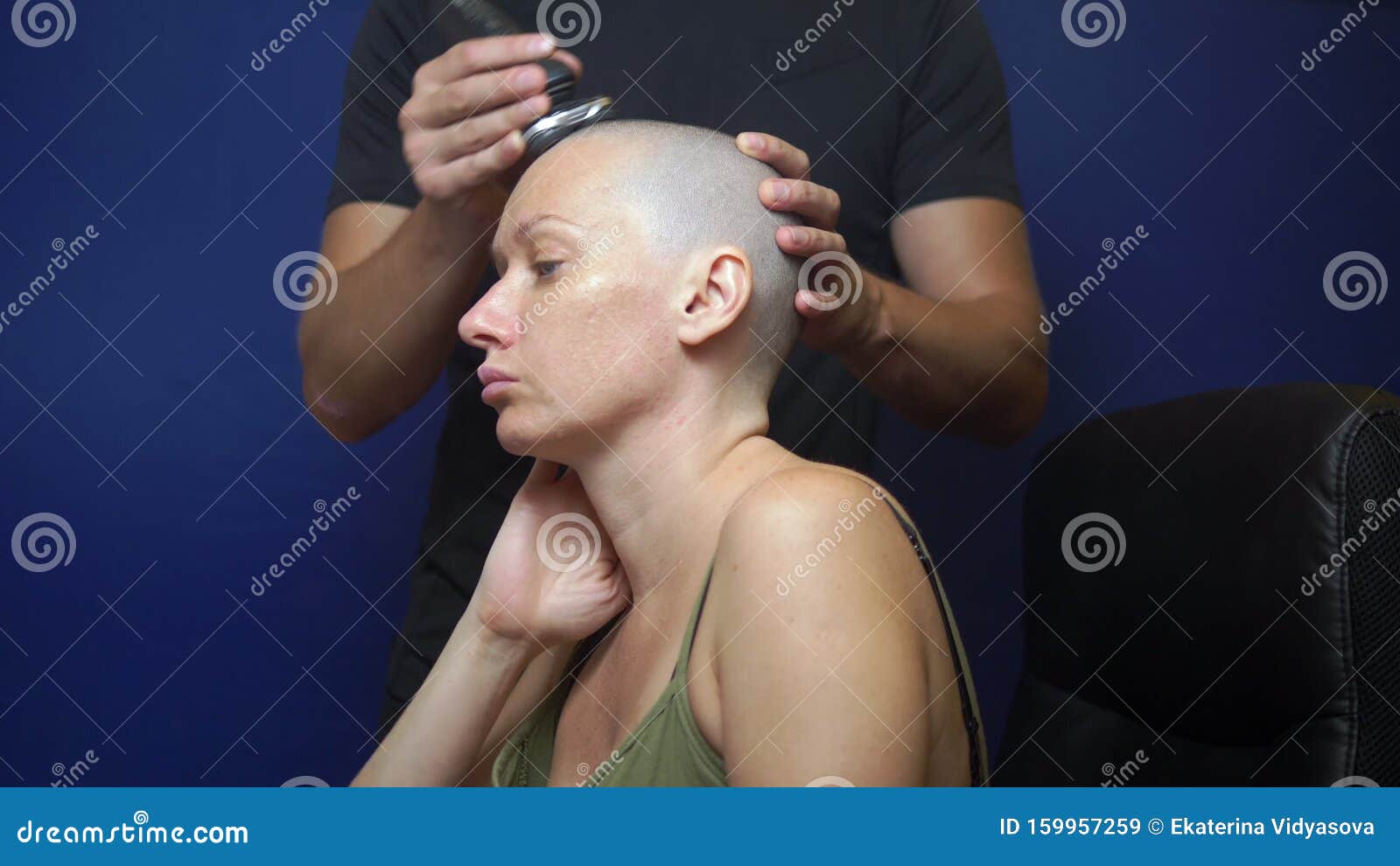 Man Shaves A Bald Woman With An Electric Razor On A Blue Background. 