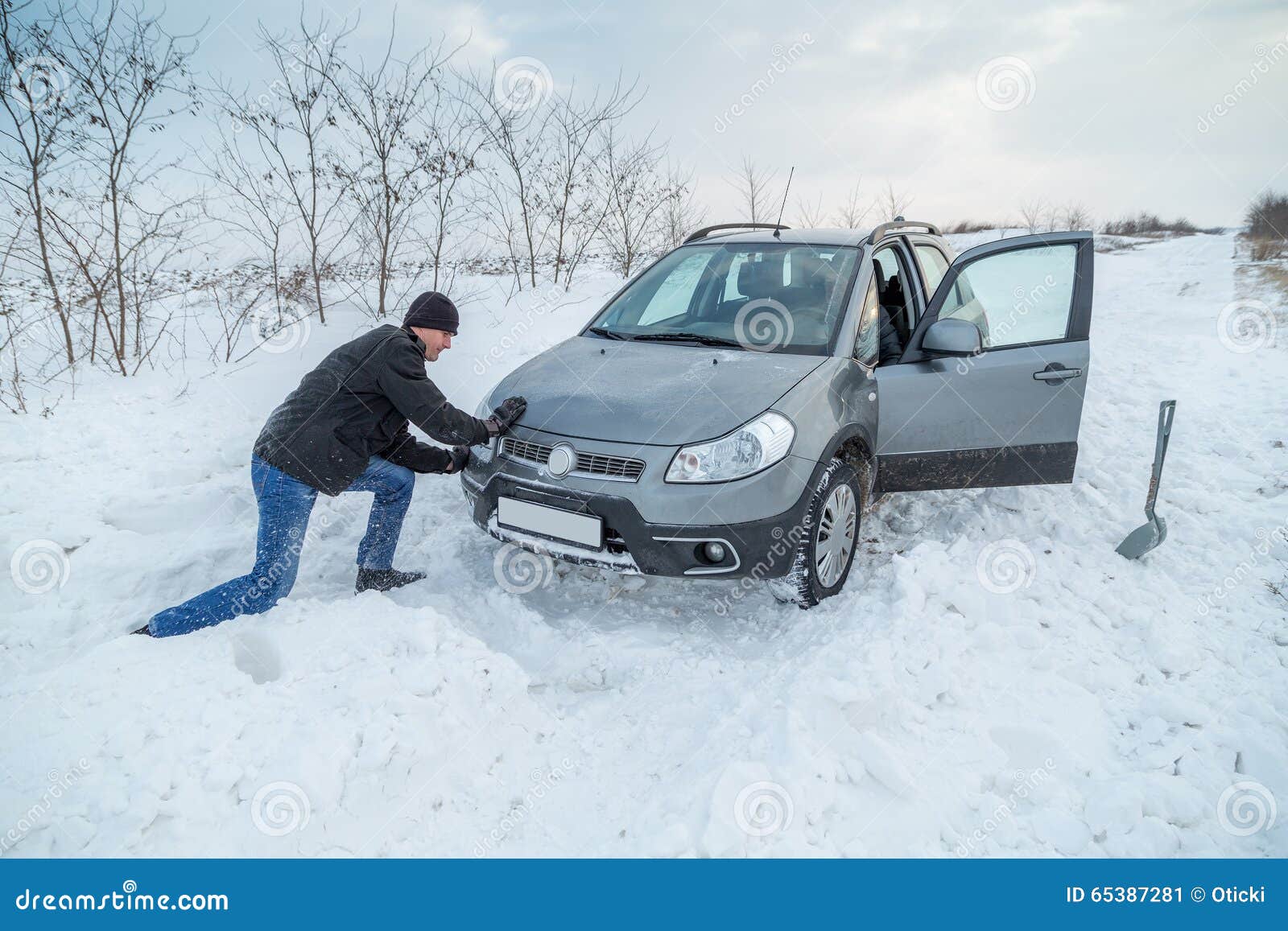 man shoveling snow to free his stuck car