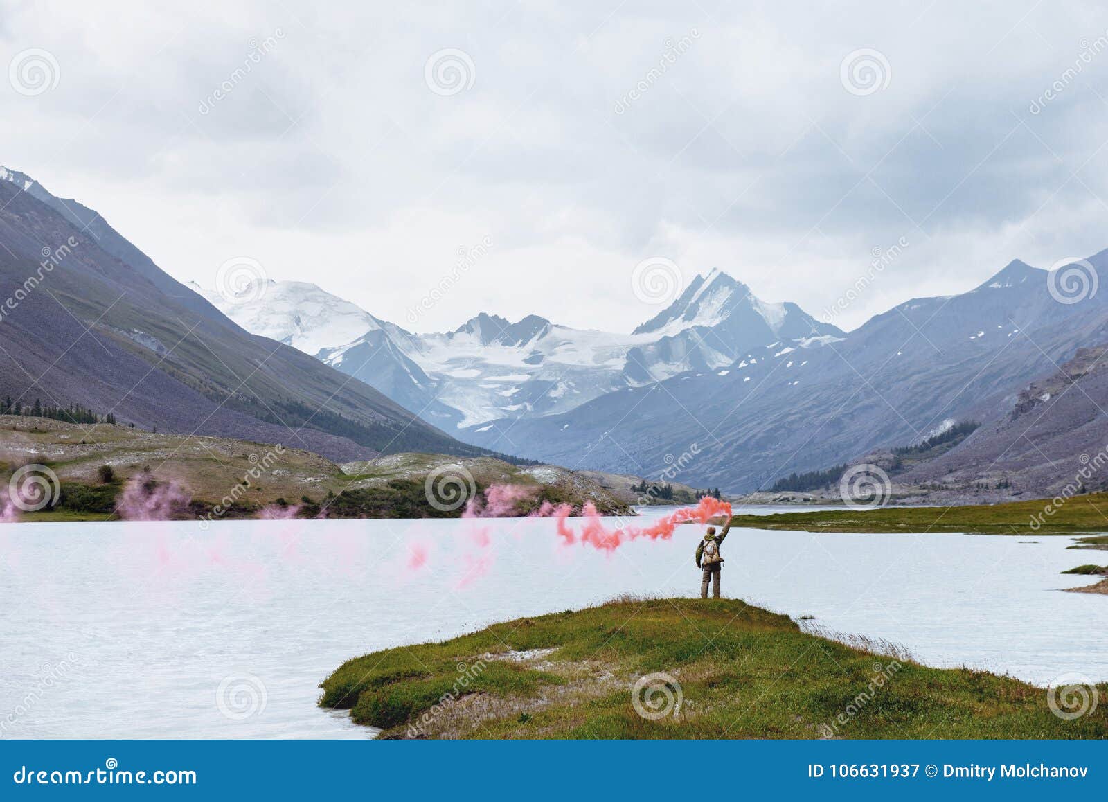 man with signal fire on background of mountain lake
