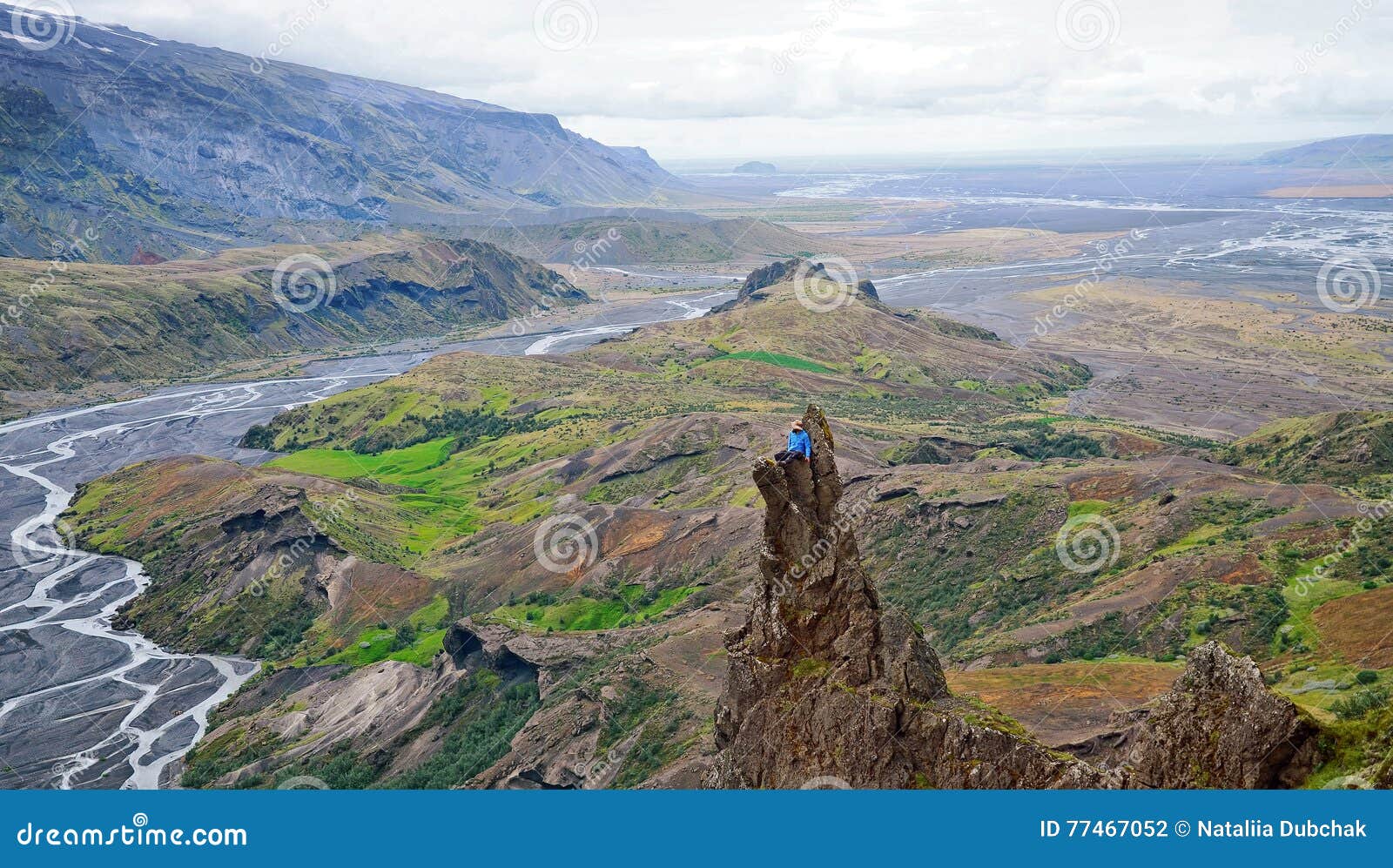 man siting on a ledge of a mountain, enjoying the beautiful view valley in thorsmork