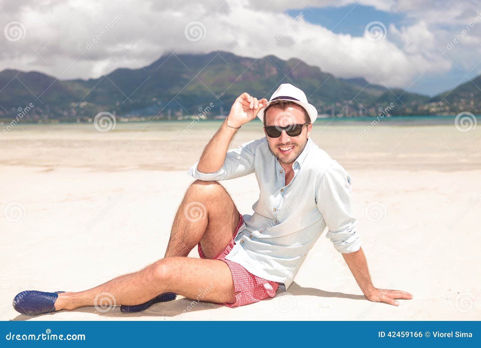 Man Sits on the Beach and Holds His Hat Stock Photo - Image of hold ...